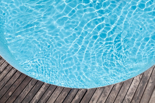 Poolside wooden deck and blue water of pool