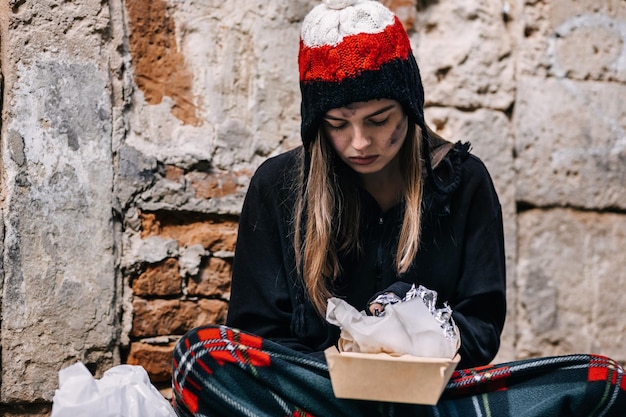 La povera sporcacciona sta mangiando un panino una ragazza affamata si siede