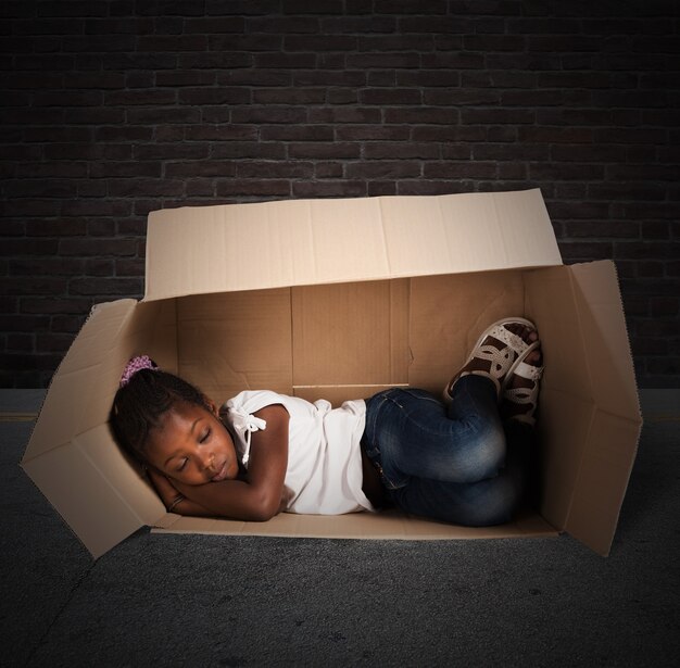 Poor little girl sleeps in a cardboard