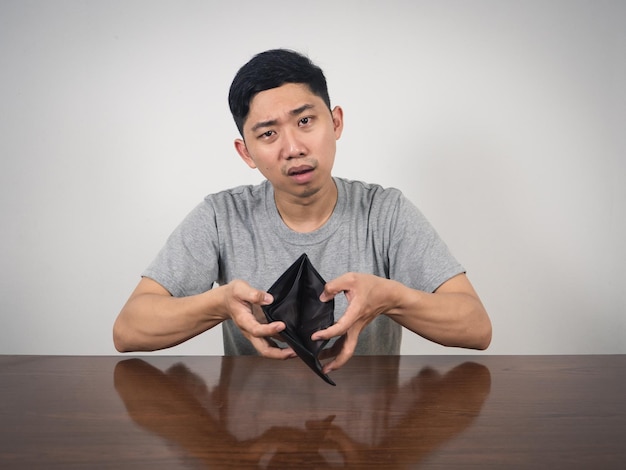 Photo poor man strain with no money show empty wallet at table