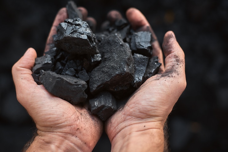 Photo poor middle-aged man holding the hands of stone coal 