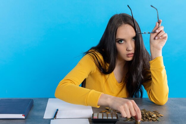 A poor young girl counts money at home at her desk hoping that she will have enough for all expenses