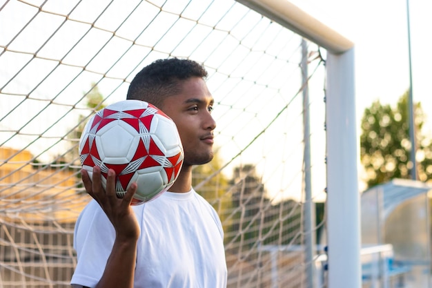 Poortwachter gooit voetbal wegkijkend in de schemering op voetbalveld