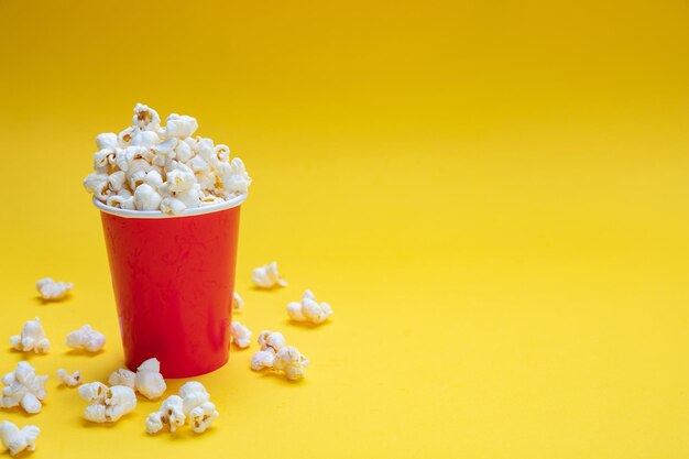 Pop corn in een papieren bekertje op gele kleur achtergrond