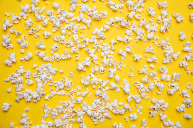 Pop corn scattered on yellow color background full frame top view