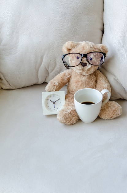 Foto popbeer en de klok met koffiekop op de bank