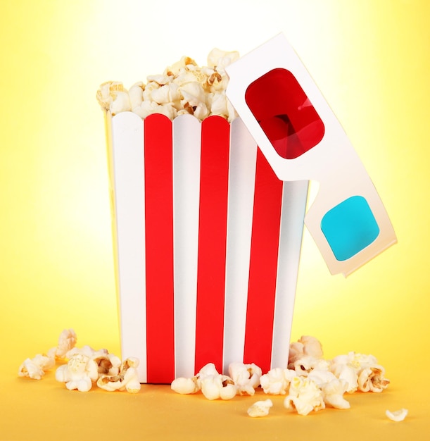 Popcorn and 3D glasses on yellow background