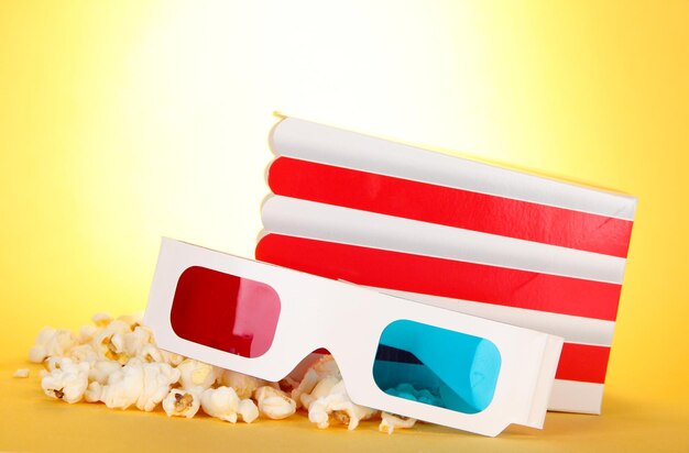 Popcorn and 3d glasses on yellow background