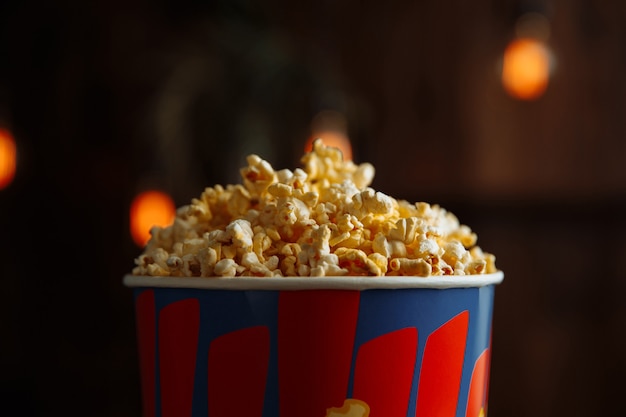 Popcorn in a bright box on wooden background. Closeup view.