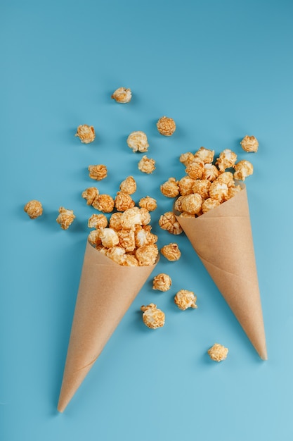 Popcorn in caramel glaze in a paper envelope on a blue