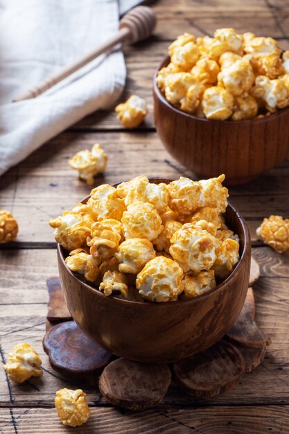 Popcorn in caramel glaze in wooden plates on a rustic table.