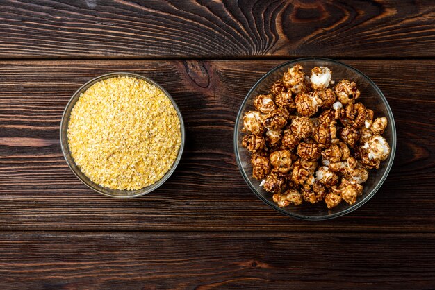 Popcorn and corn flakes on dark wooden background.