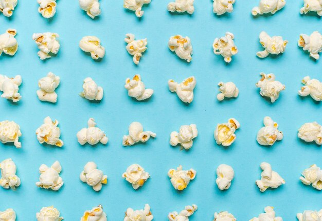 Photo popcorn flakes aligned on a blue background popcorn pattern top view