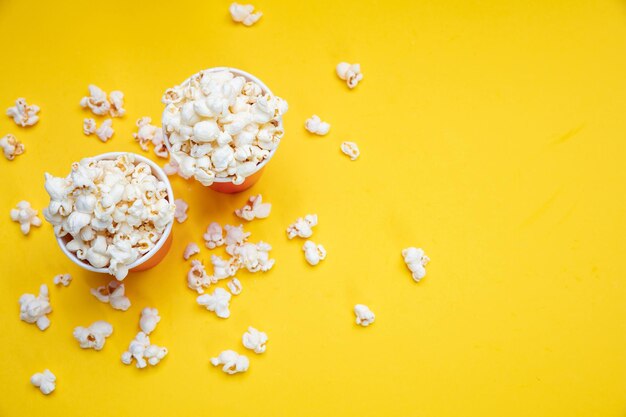 Popcorn in rode papieren bekers op gele kleur achtergrond