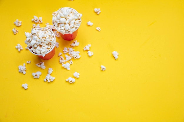 Popcorn in rode papieren bekers op gele kleur achtergrond