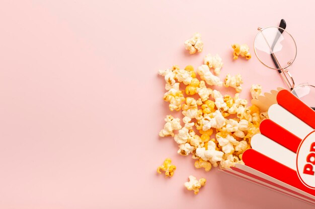 Popcorn is scattered over a pink background Empty space for text