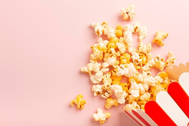 Popcorn is scattered over a pink background Empty space for text