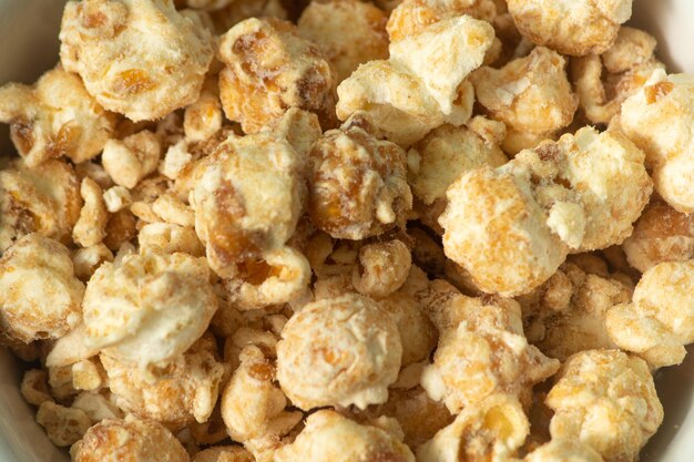 Foto popcorn met boterkaramelsmaak op een witte kom en witte achtergrond