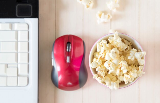 Popcorn met computer op houten achtergrond, ondiepe nadruk.