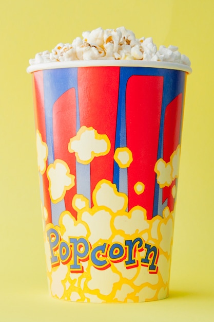 popcorn in a red and white cardboard box on a yellow background. . flat lay