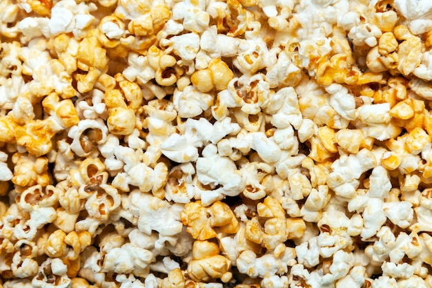 Popcorn textuur achtergrond. een stapel popcorn achter het glas