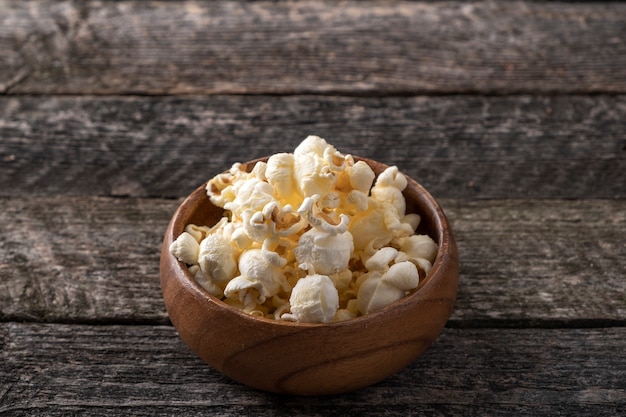 Popcorn in a wooden bowl in rustic style. Text space