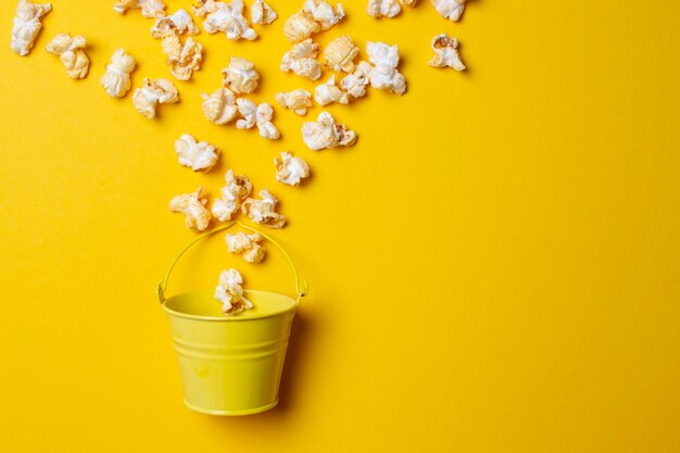 Popcorn on a yellow background in a yellow bucket