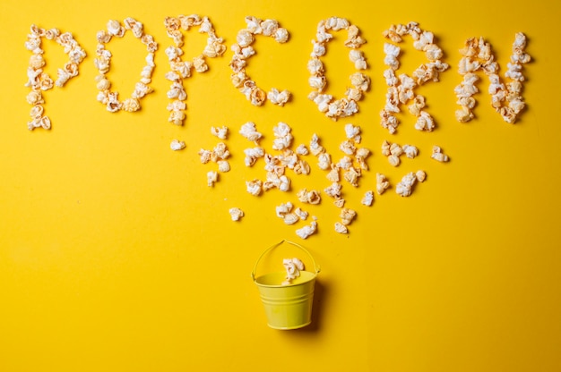 popcorn on a yellow background in a yellow bucket