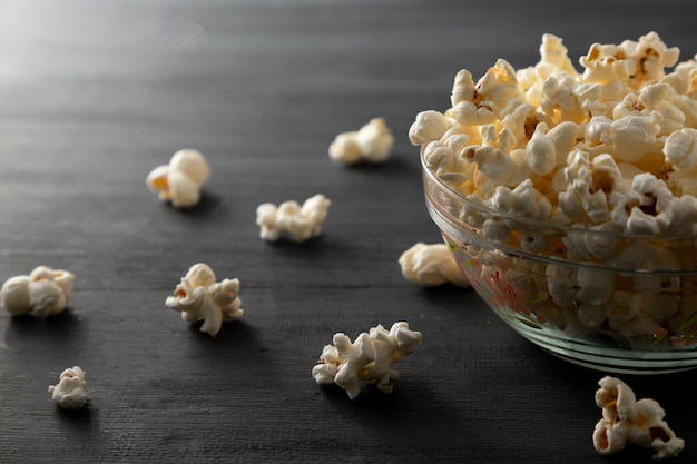 Popcornkom omgedraaid op een zwarte houten tafel Popcorn verspreid over de tafel