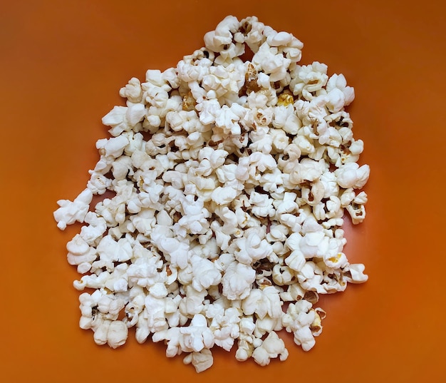 Popcornvoedsel in rode emmer. Witte popcorn heerlijke snack op de gele achtergrond.