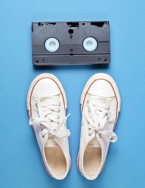 Popcultuurattributen met retro witte sneakers en videoband