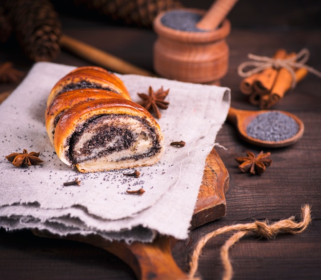 Poppy roll on a gray linen napkin and poppy seeds 