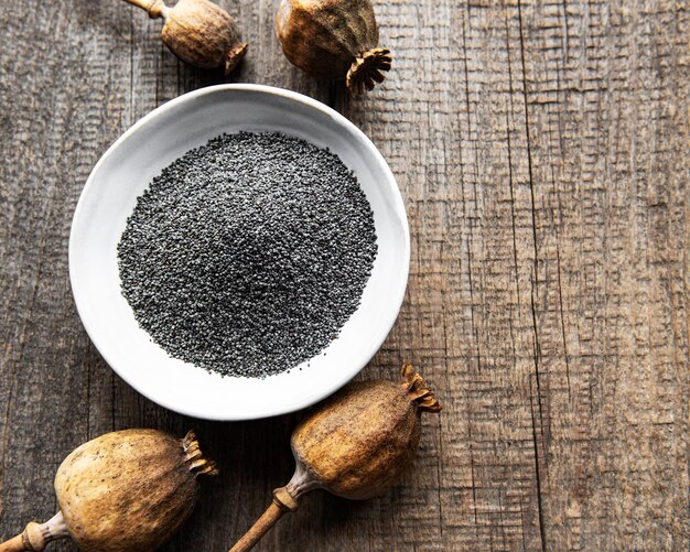 Poppy seeds in small wooden bowl on the wooden background