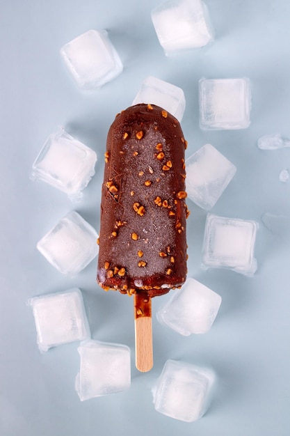 Popsicle in chocolate and ice cubes on a blue background selective focus