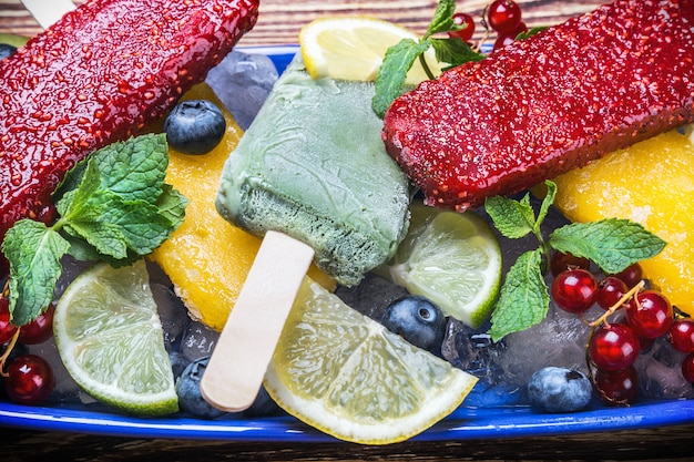 Popsicles with berries and fruit on a wooden table