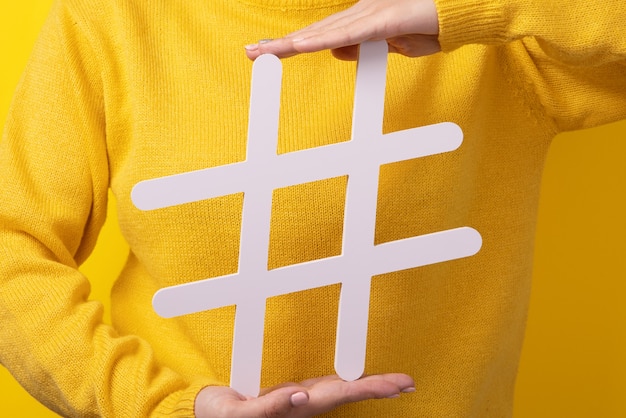 Popular blog posts, trendy content, hands holding hashtag sign over yellow background