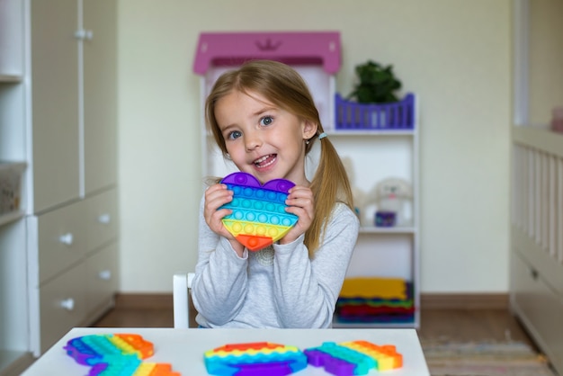 popular game pop it the child holds a silicone flexible toy for the development of fine motor skills