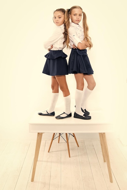 Popular girls in classroom School friendship Schoolgirls tidy appearance school uniform Childhood happiness School day Kids cute school students stand on table On same wave On the top