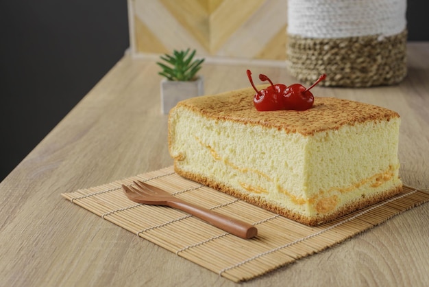 Popular Japanese dessert or sponge cake of castella with cherry on top served on a wooden table