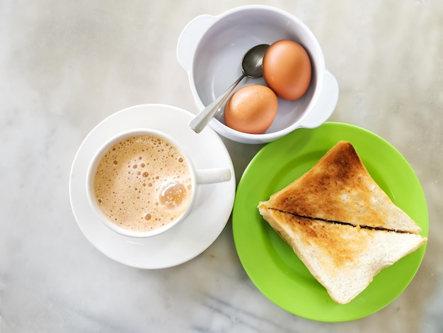 Popular Malaysian breakfast set. Milk tea or teh tarik, half boiled eggs and kaya butter toast set.