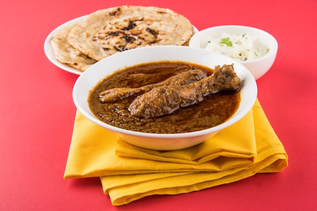 Popular reddish Chicken Curry or Masala, with prominent Leg Piece, served in a bowl with Pilau Rice, Chapati or Roti and salad