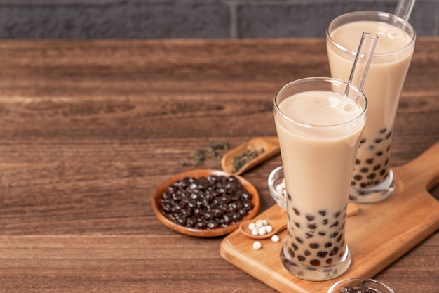 popular taiwan drink bubble milk tea with tapioca pearl ball in drinking glass and straw wooden table