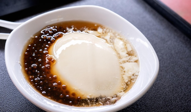 popular taiwan gourmet dessert of tapioca pearl ball bubble mixed bean curd tofu pudding douhua dou hua in white bowl close up lifestyle