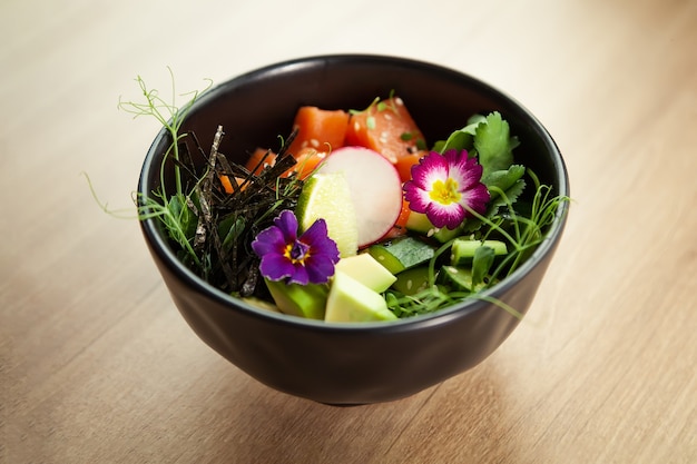 Por met zalm in een kom ingrediënten verse zalm avocado komkommer rijst tamarinde saus mangosaus nori limoen sesamzaad koriander zeevruchten concept Aziatische zalm poke salade op