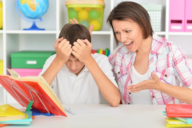 Porait of emotional mother with her son doing homework at home