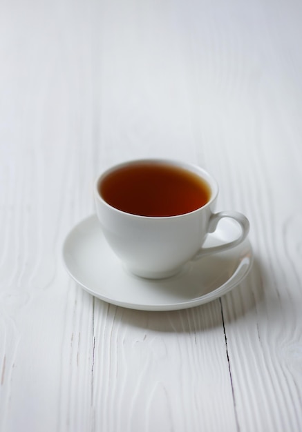 A porcelain cup of hot tea on a light wooden table Soft focus