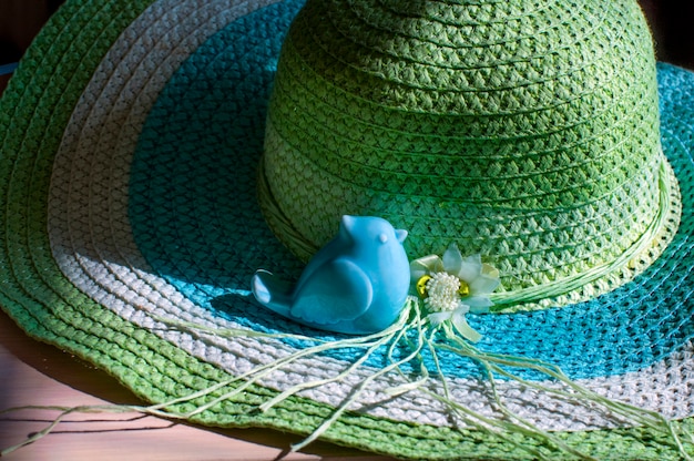 Foto figura in porcellana di un uccello su un cappello di paglia estivo.