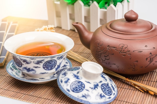 Porcelain teapot and teacup on white background