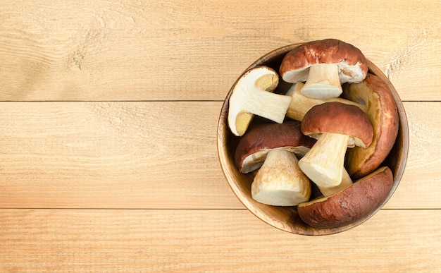 Porcini mushrooms (cep) in a wooden plate on a wooden table