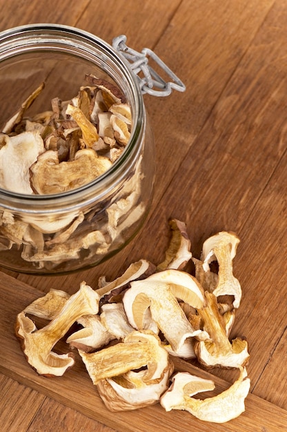 Белые грибы, нарезанные ломтиками и сушеные, используются для приготовления вегетарианских блюд. Сушеные белые грибы на деревянном кухонном столе.